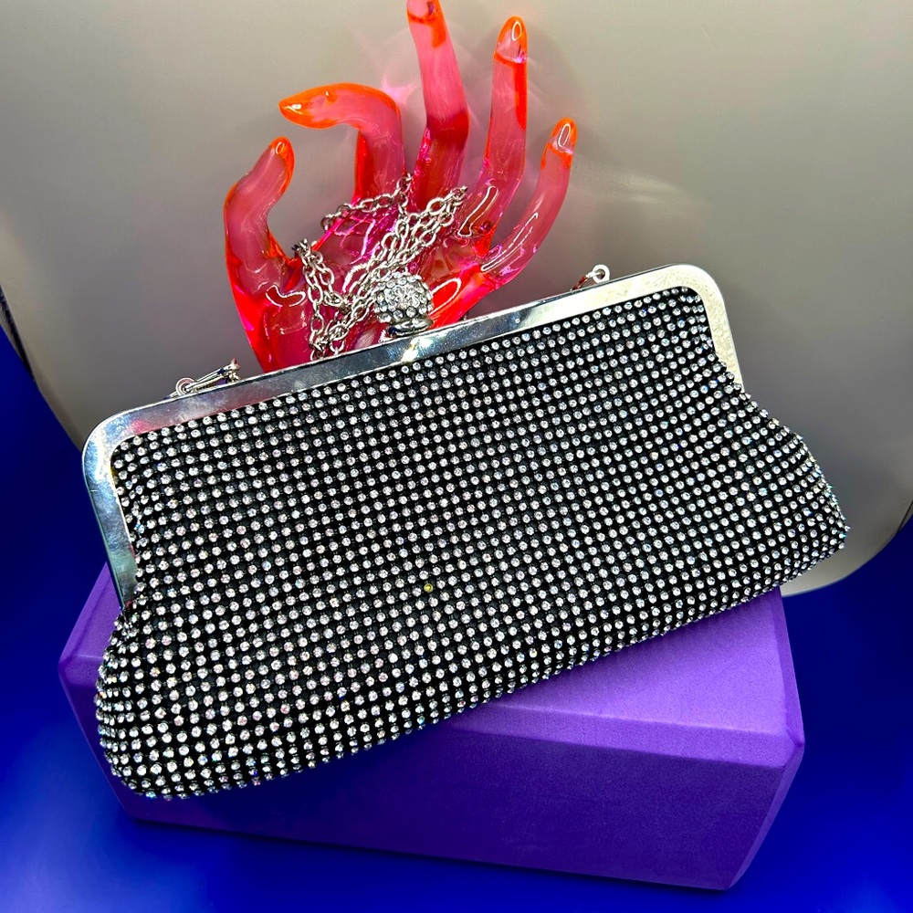 Black clutch bag with rhinestones, kiss lock closure and detachable chain.